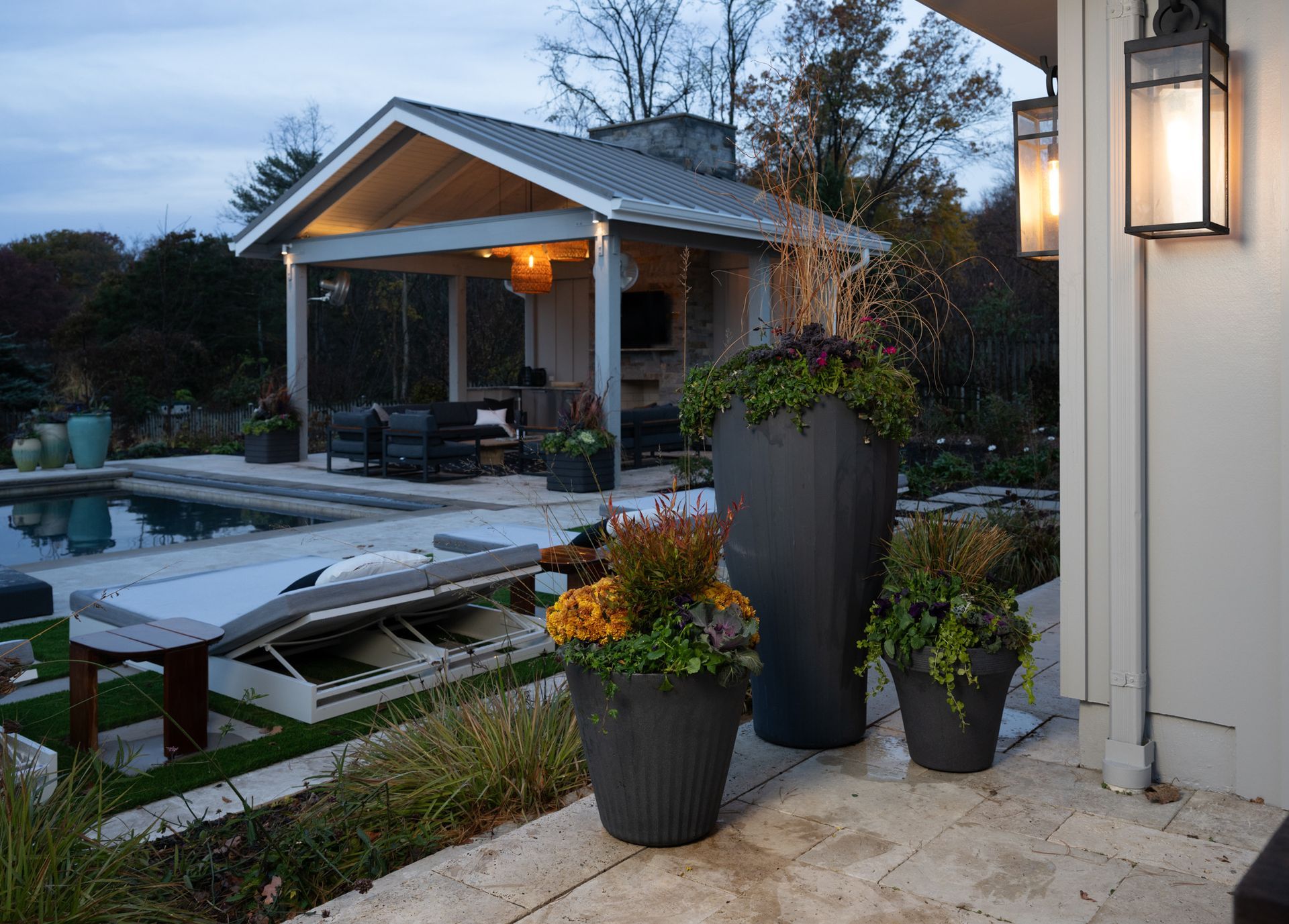Poolside patio with a covered seating area and planters filled with flowers and plants.
