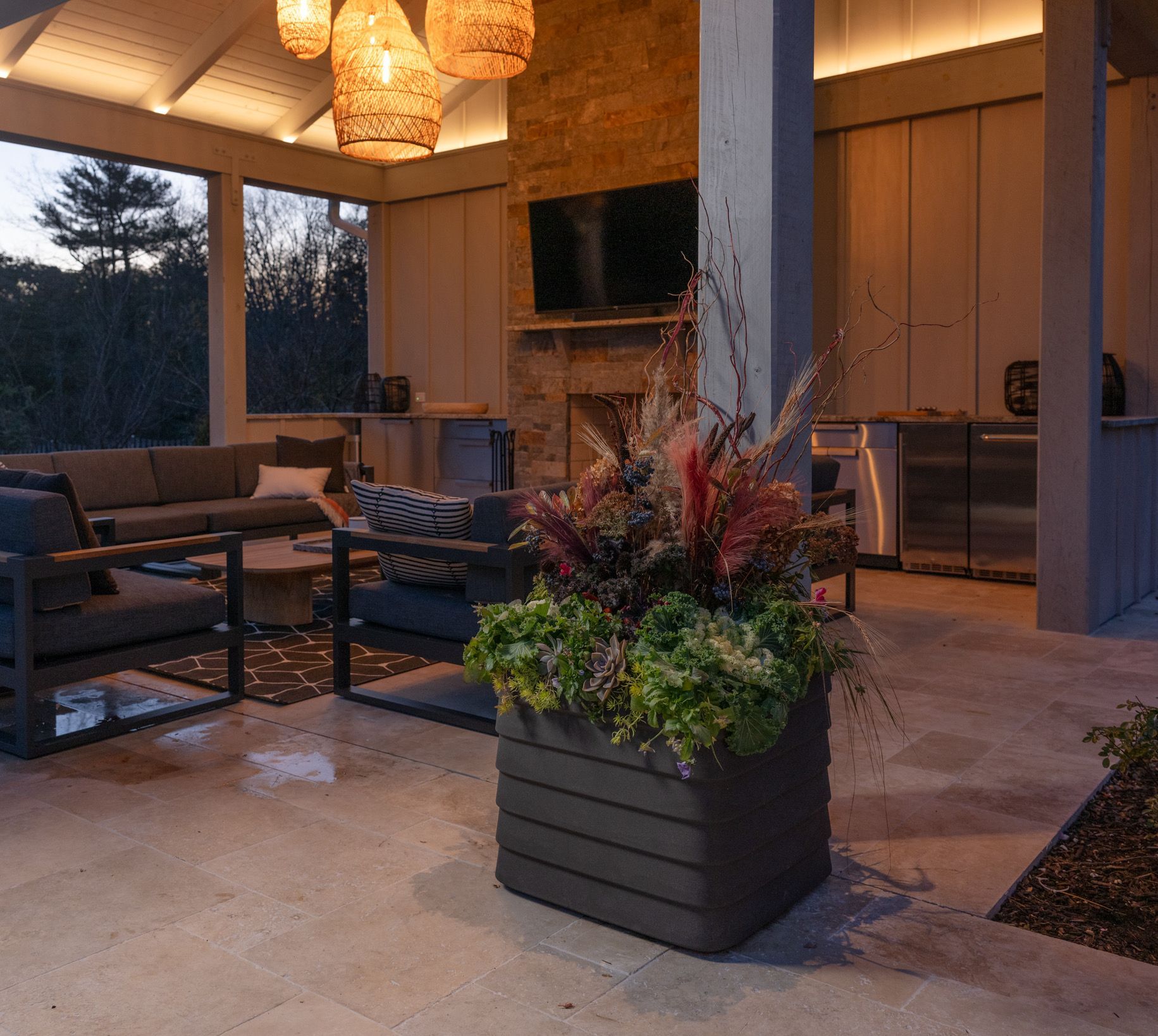 Outdoor patio with a large planter box filled with plants; a seating area and fireplace are visible.