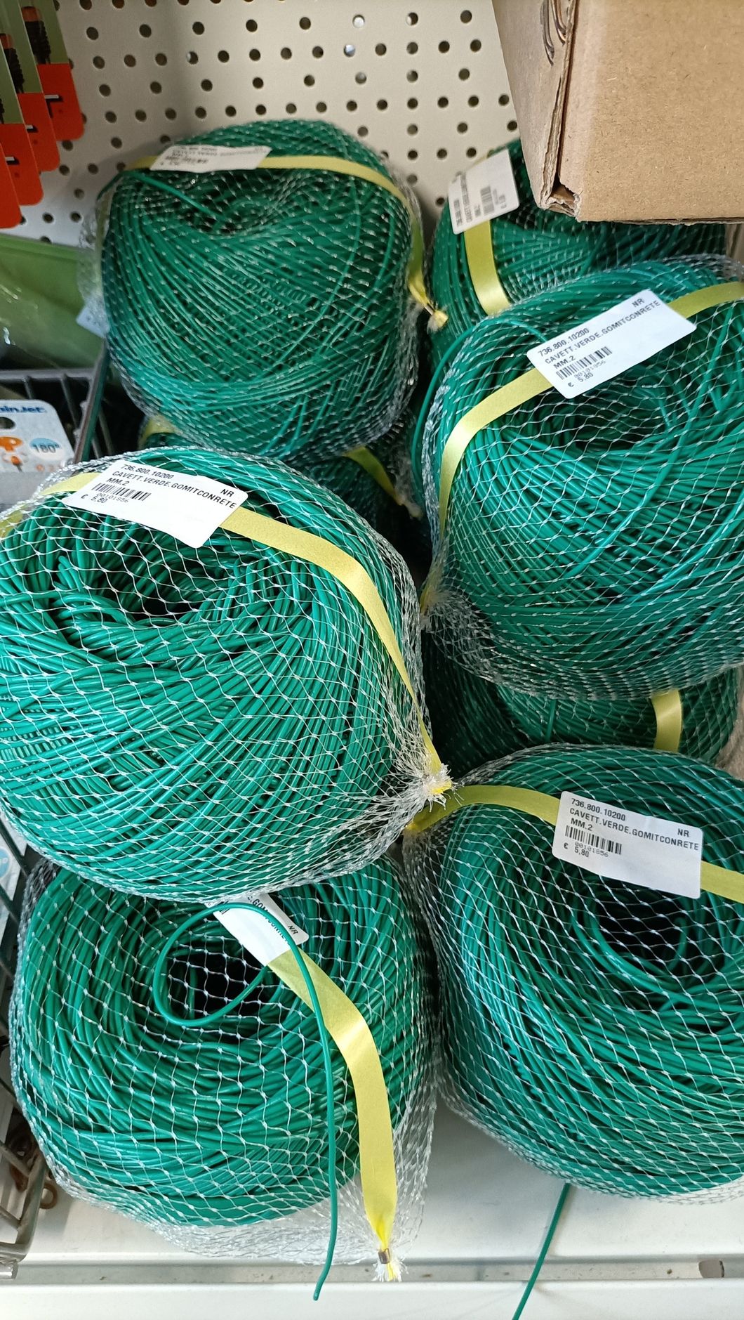 Rotoli di rete verde legati con cinghie gialle su uno scaffale di un negozio.
