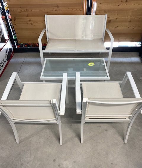 Set da giardino in metallo bianco con due sedie e una panca attorno a un tavolo con piano in vetro, ideale per interni.
