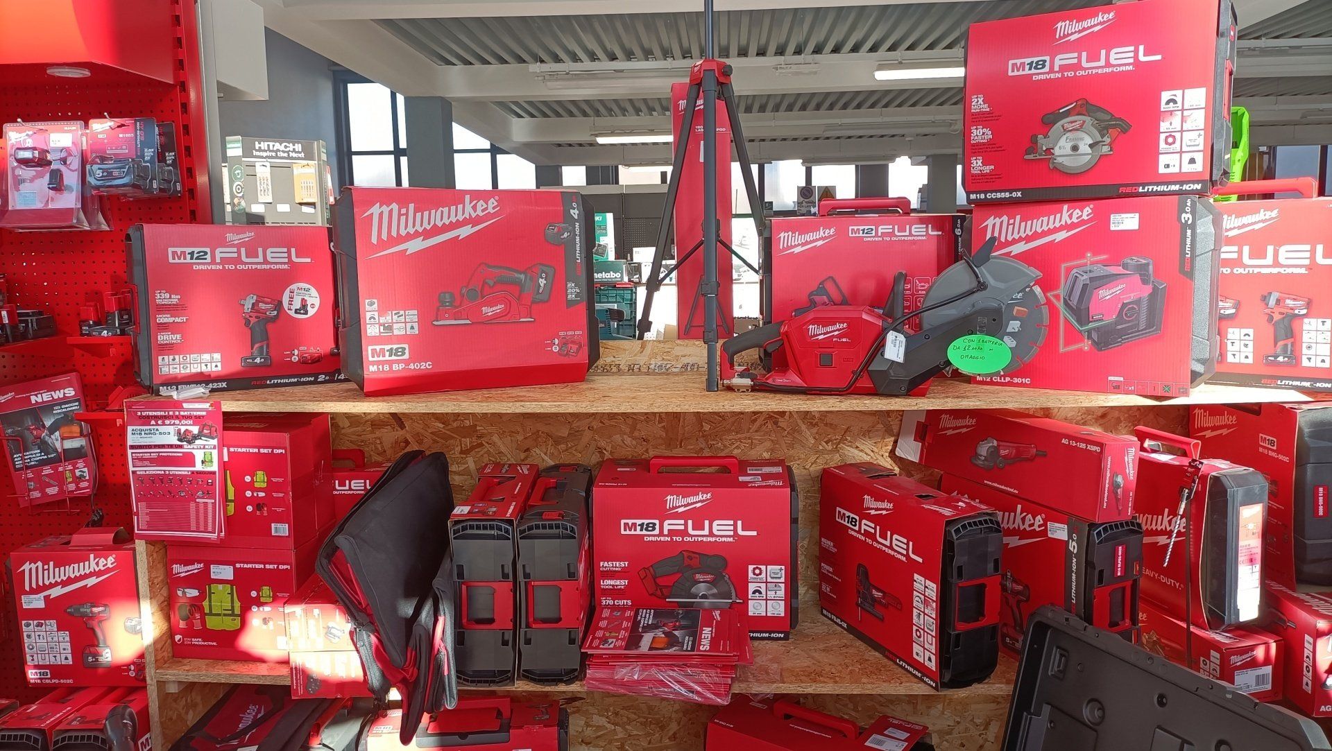 Espositore di prodotti rossi con scatole e sacchetti impilati sugli scaffali di un negozio.