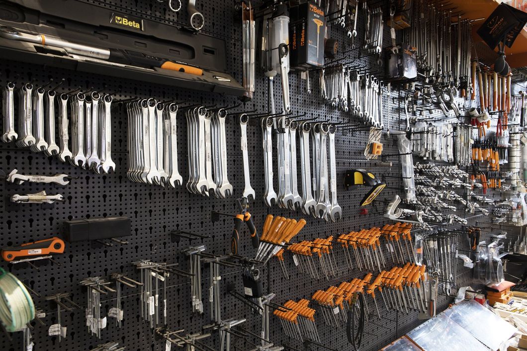 Parete dell'officina con utensili manuali appesi e ordinatamente disposti su un pannello forato.