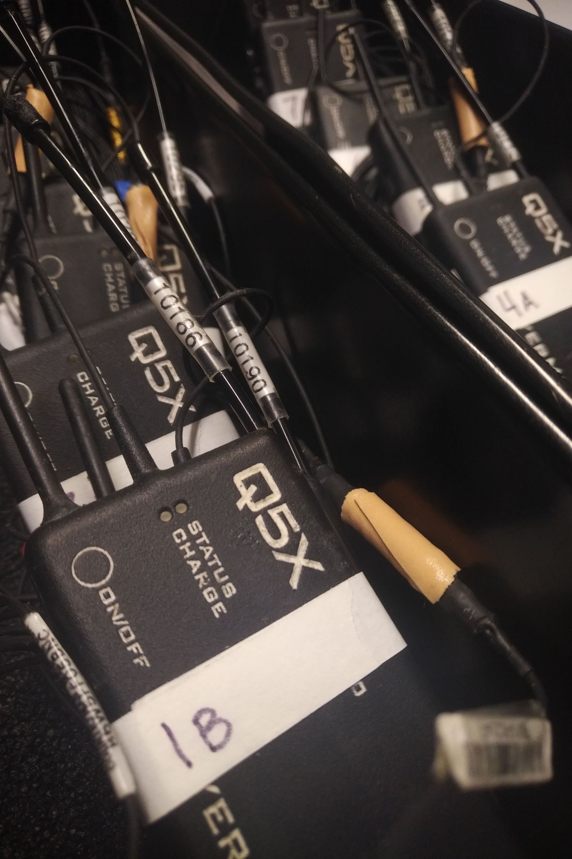 Two bins of Q5X PlayerMics in the field with tape labels