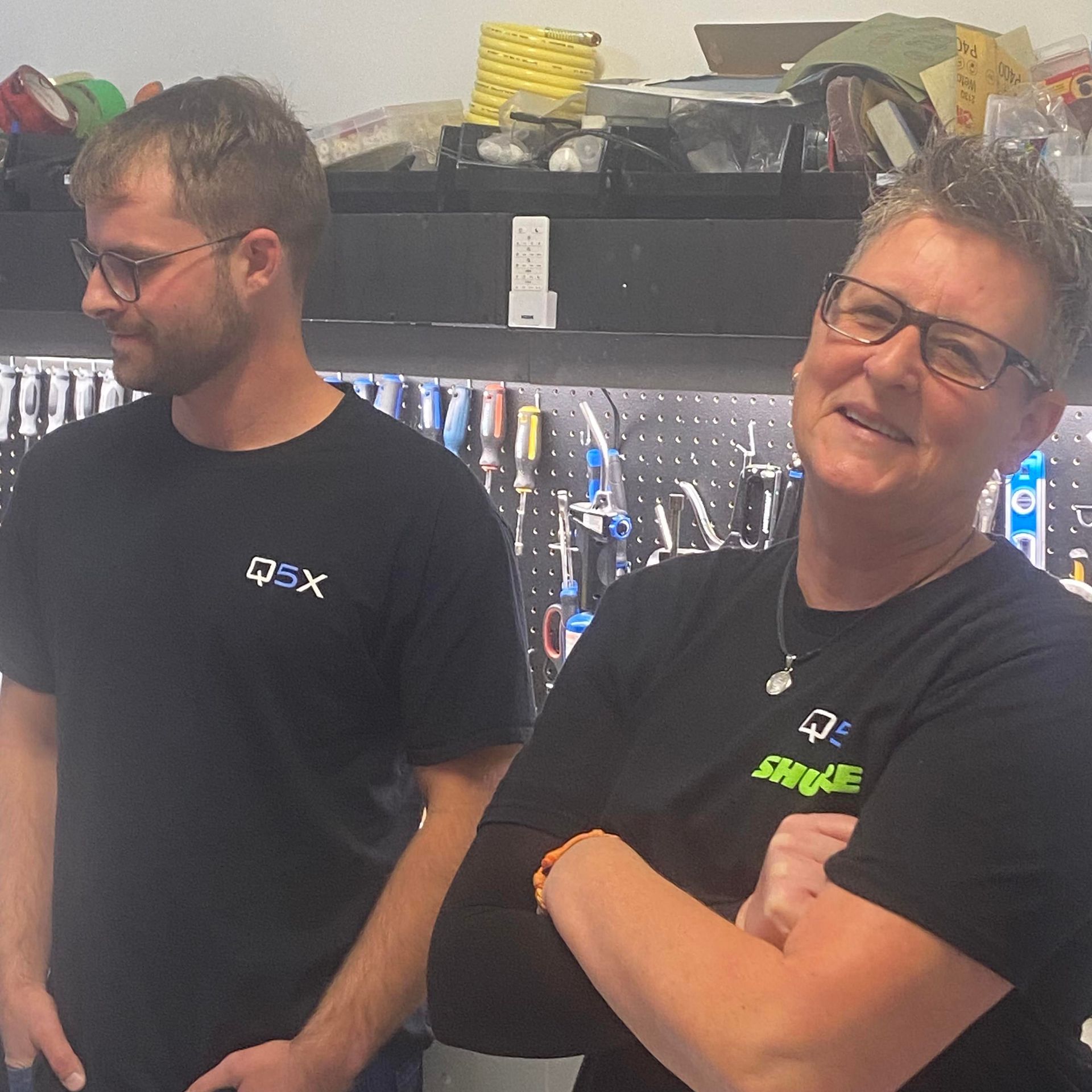 Q5X employees smiling sharing a moment in the company machine shop