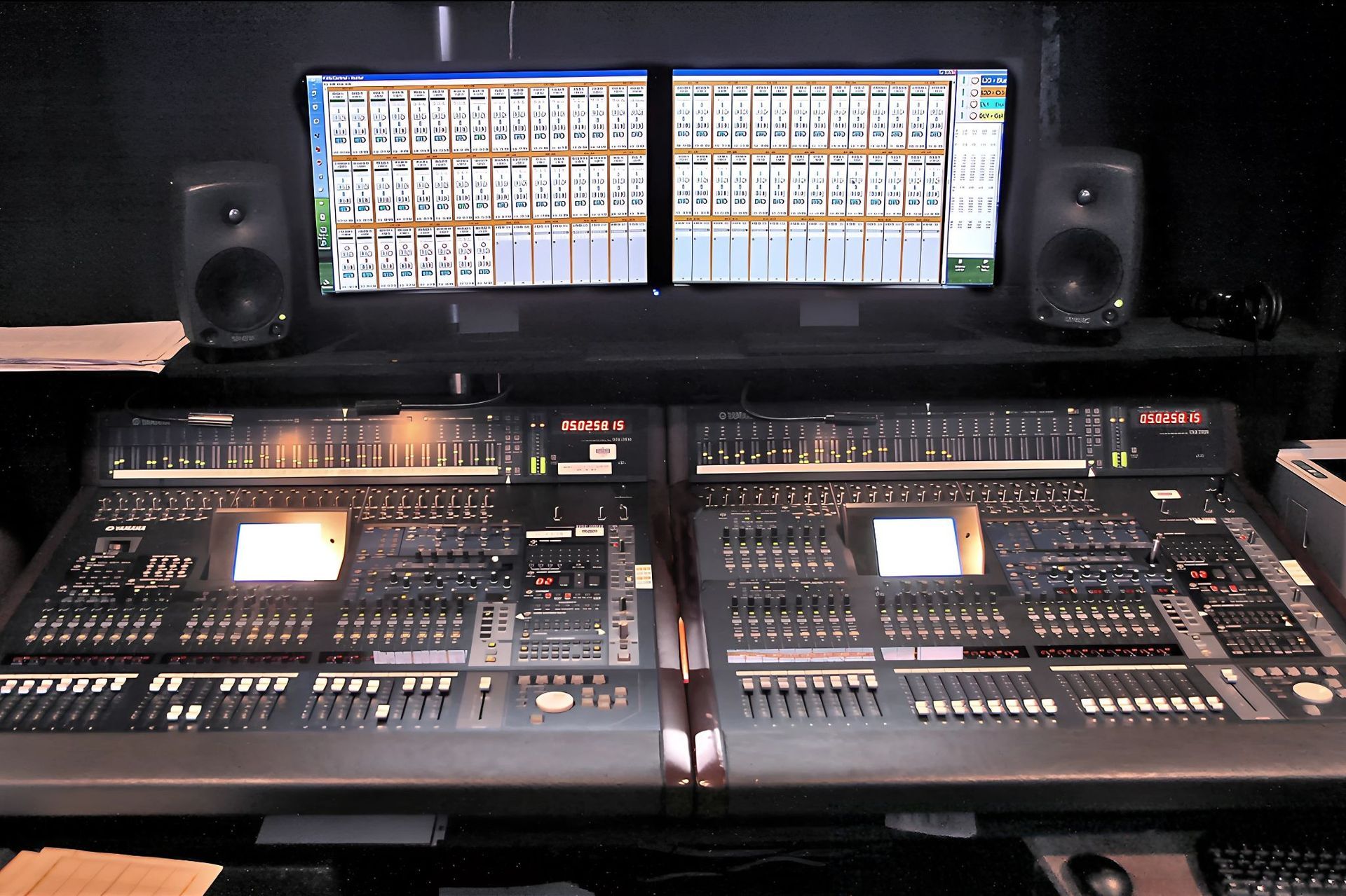 Sound mixer boards with two monitors running Q5X MicControl software above them