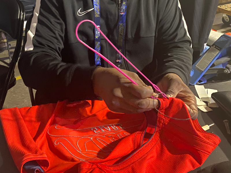 A1 audio technician routing a microphone cable in a NBA jersey