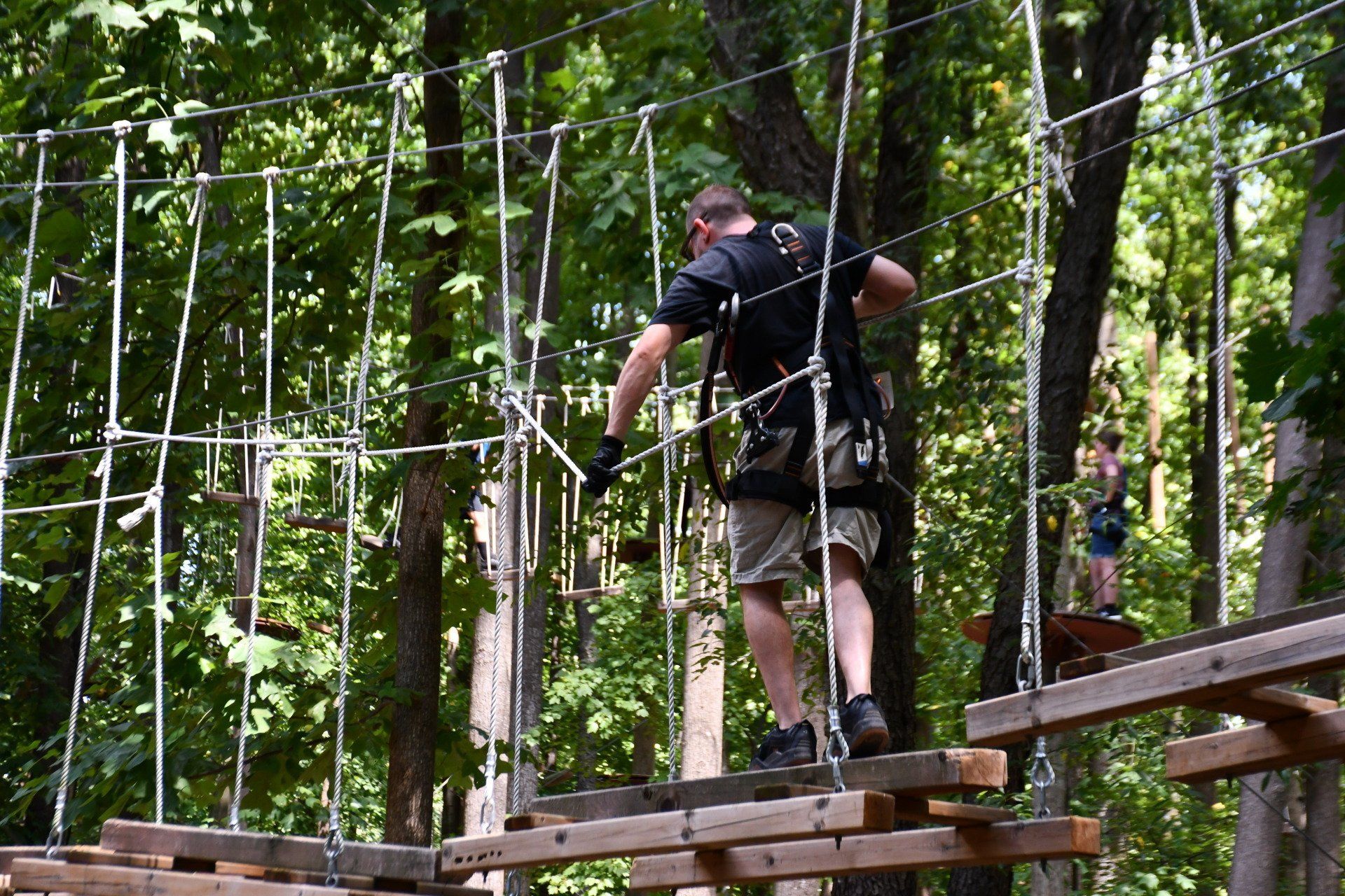 Male climber climbing on a walking bridge in the trees