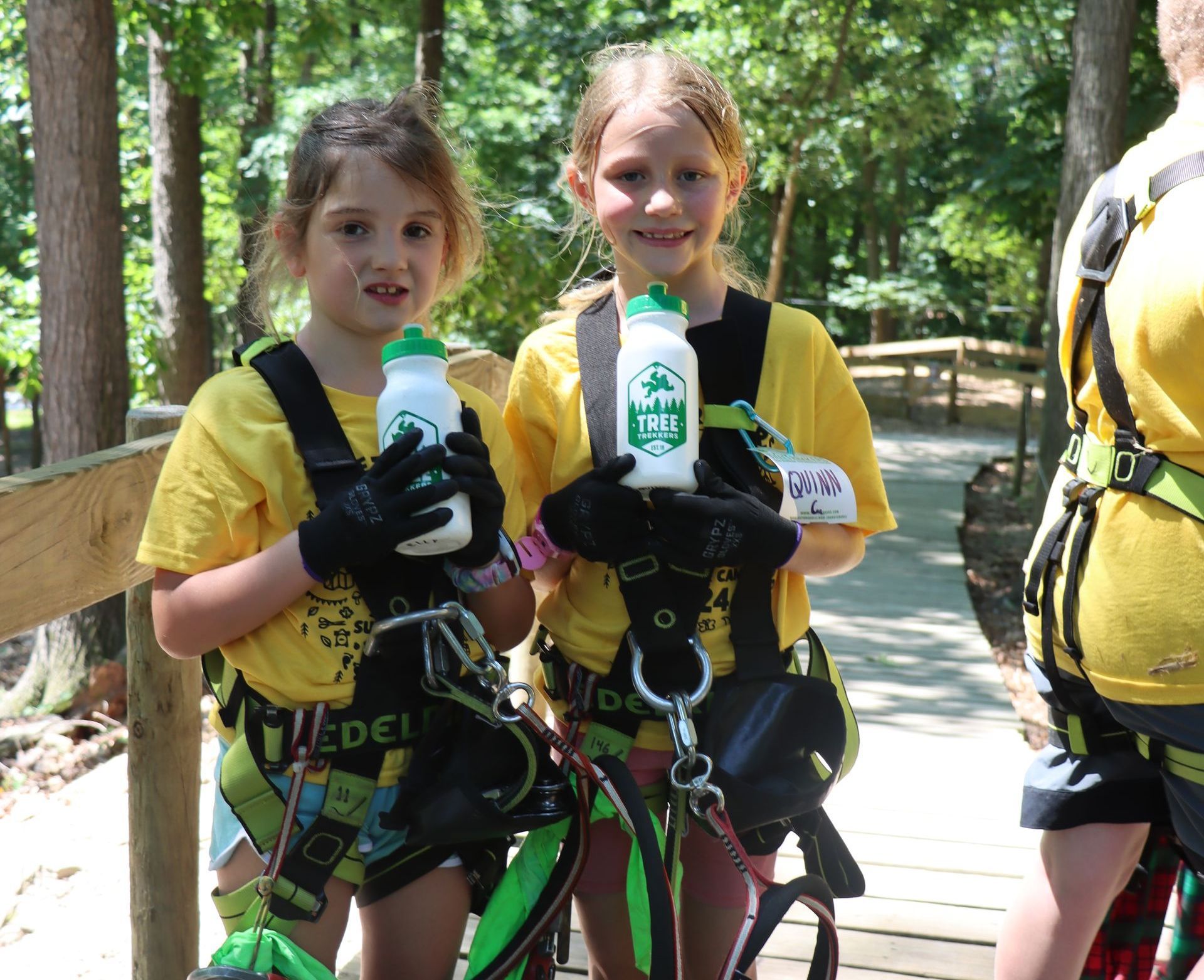 Two young girls are standing next to each other holding water bottles.