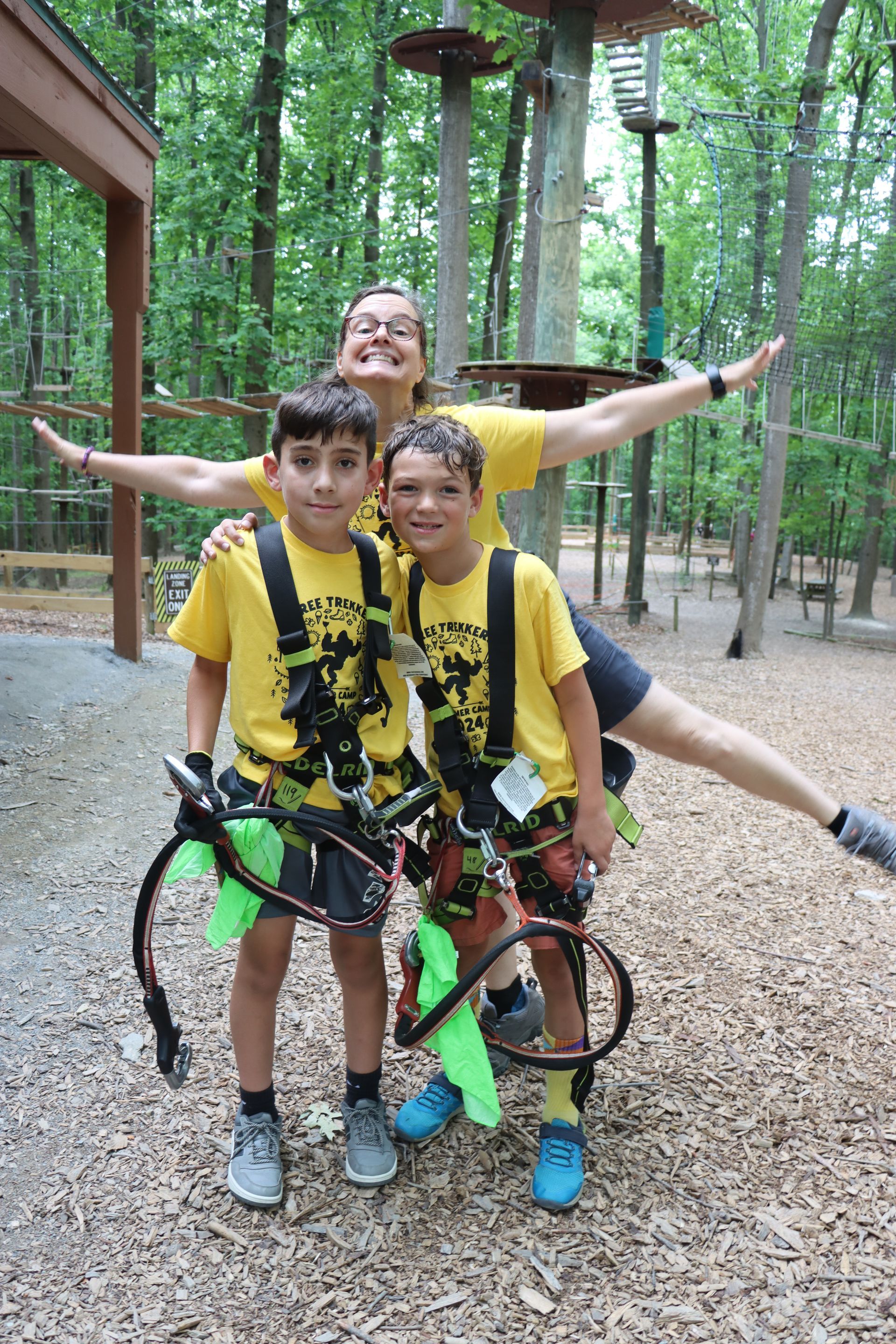 A woman is posing for a picture with two boys wearing harnesses.