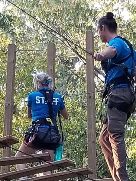 Female and male staff climbing on high ropes course