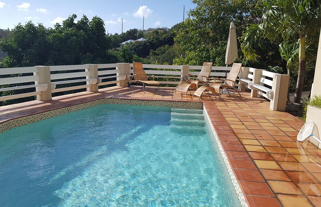 A villa with pool and chairs.