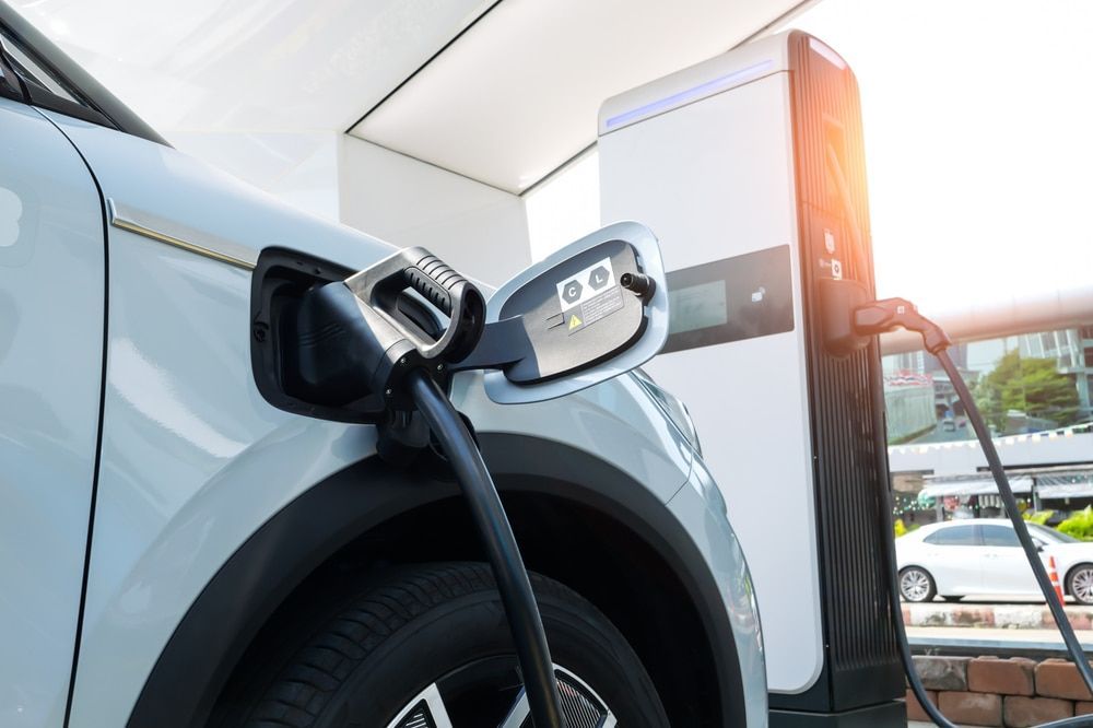 White electric vehicle charging at a charging station