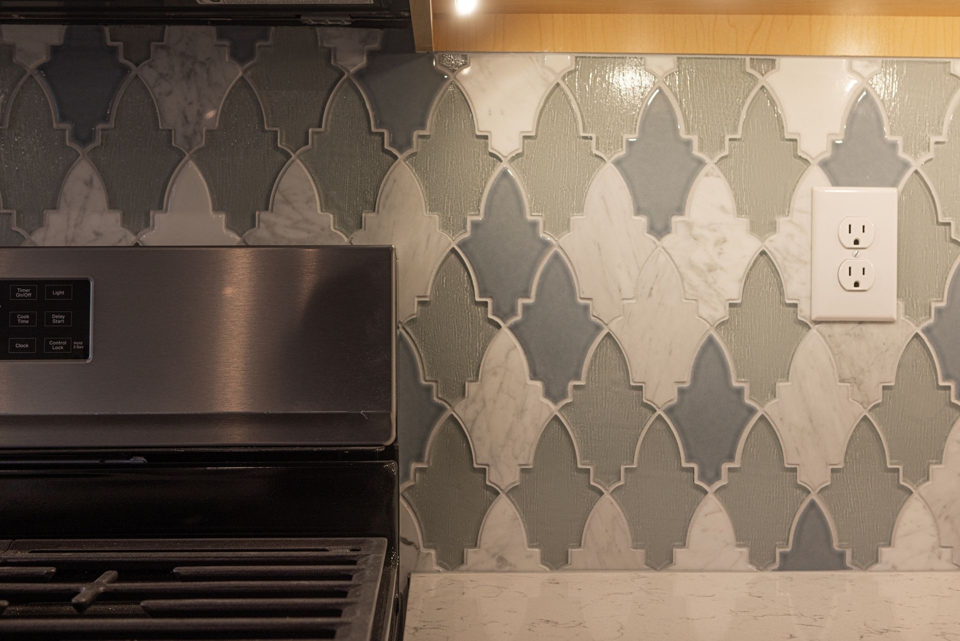 A kitchen with a stove and a wall with tiles.
