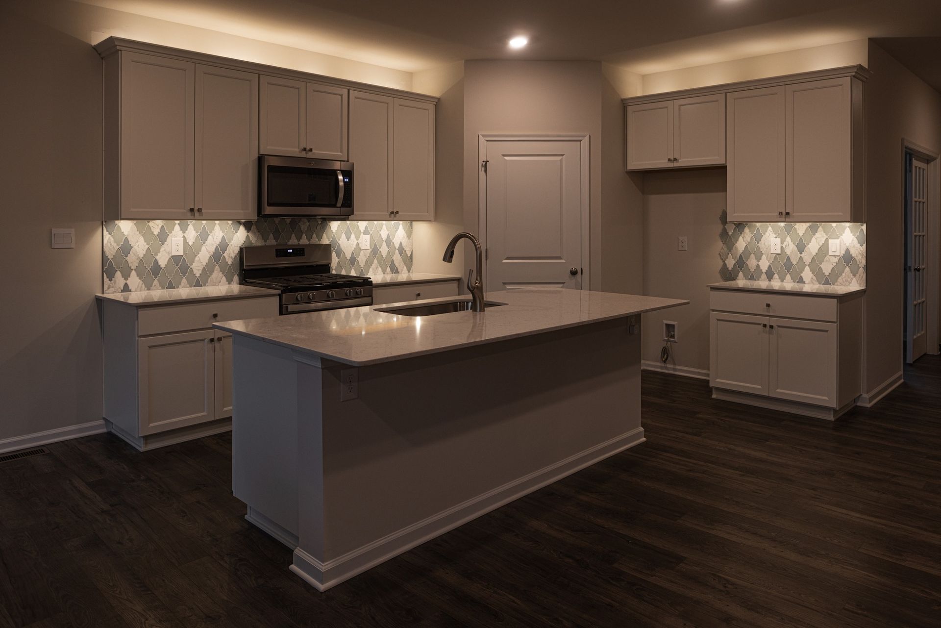 A kitchen with white cabinets , stainless steel appliances , and a large island.