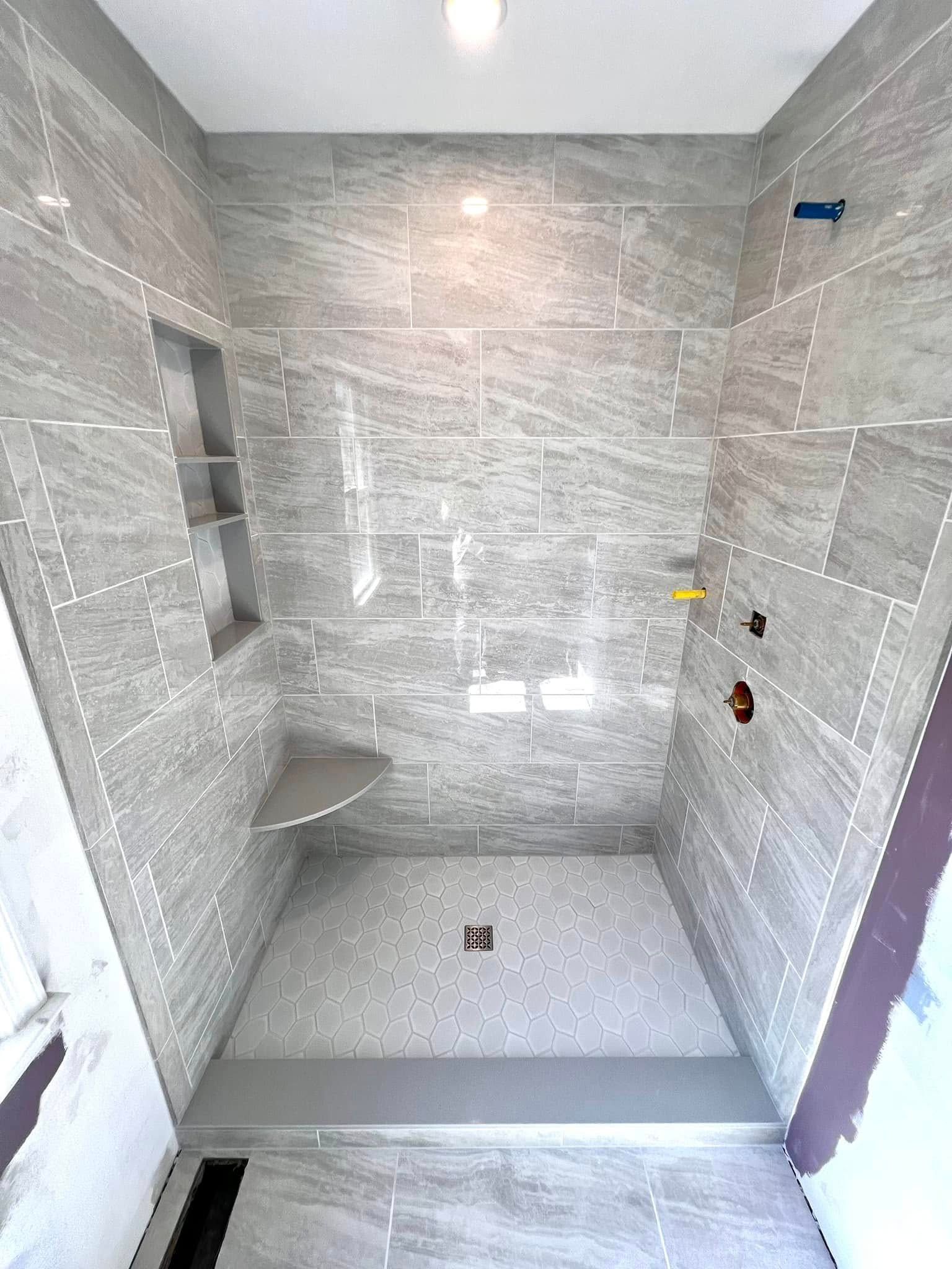A bathroom with a walk in shower and a bench.