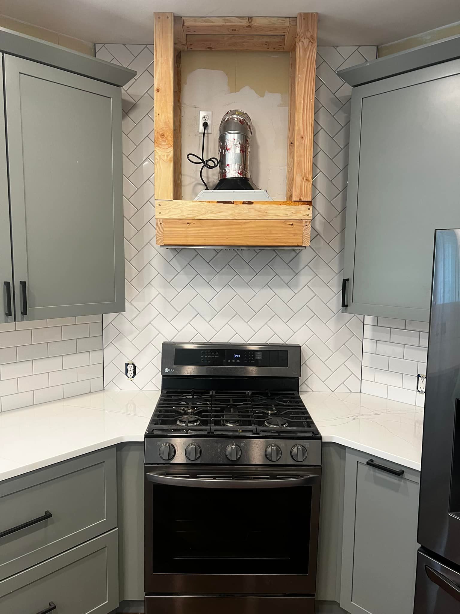 A kitchen with a stove and a refrigerator and a wooden shelf above the stove.