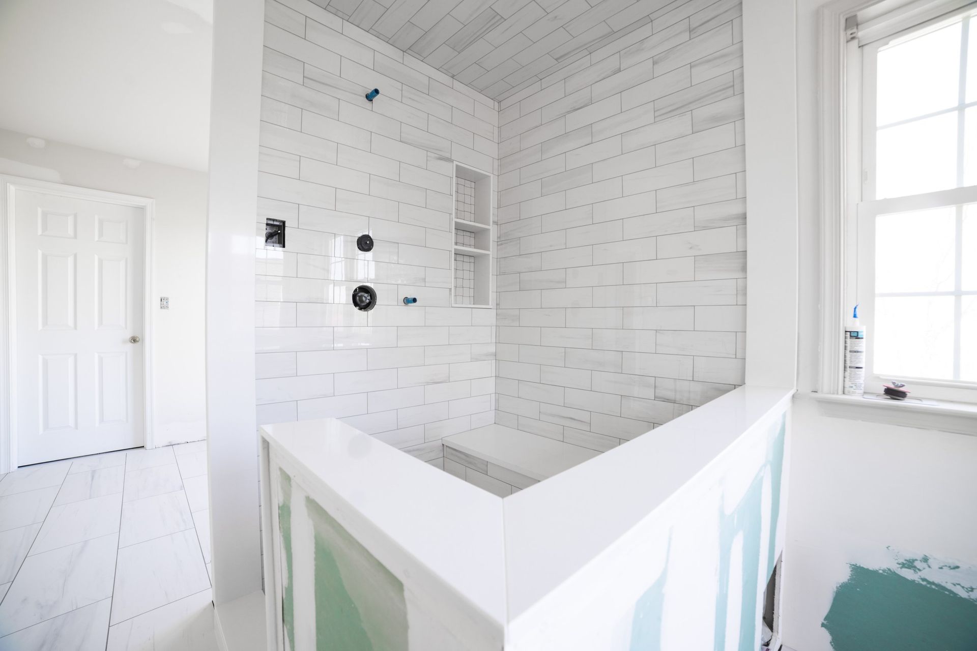 A bathroom with white tiles and a window.