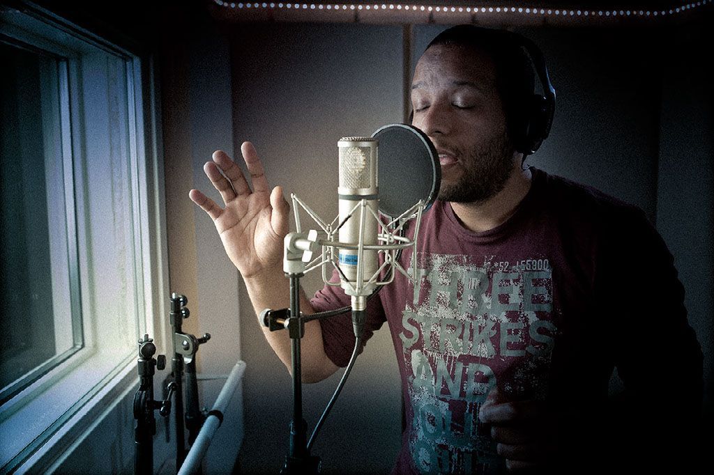 Singer with ribbon microphone in vocal booth with isolation acoustics