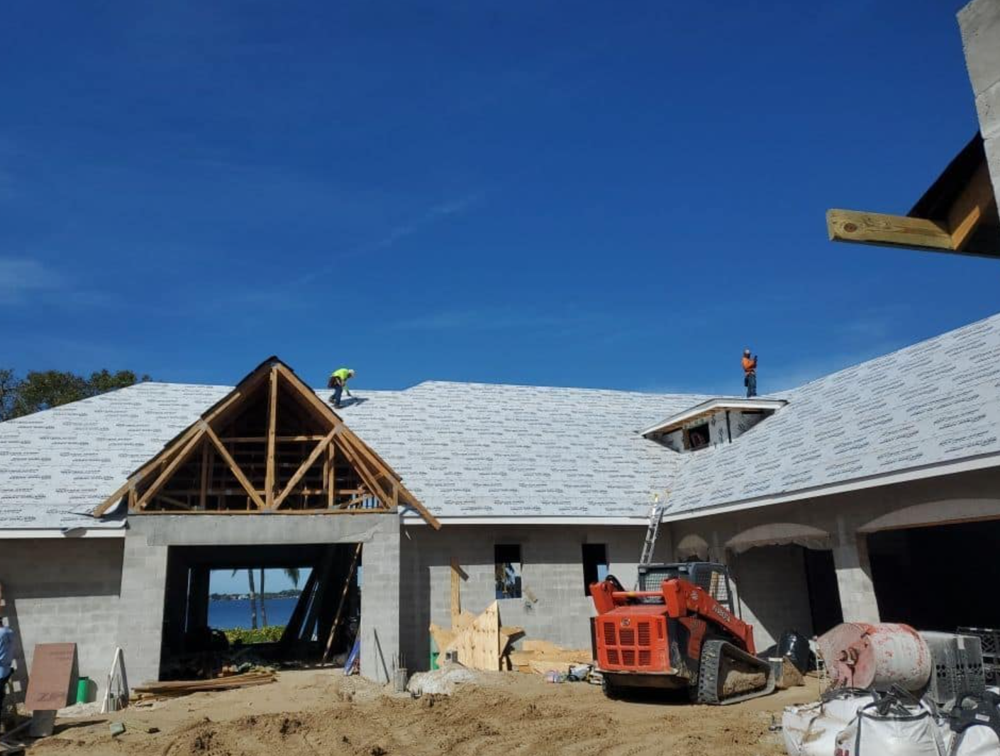 Construction workers are working on the roof of a house