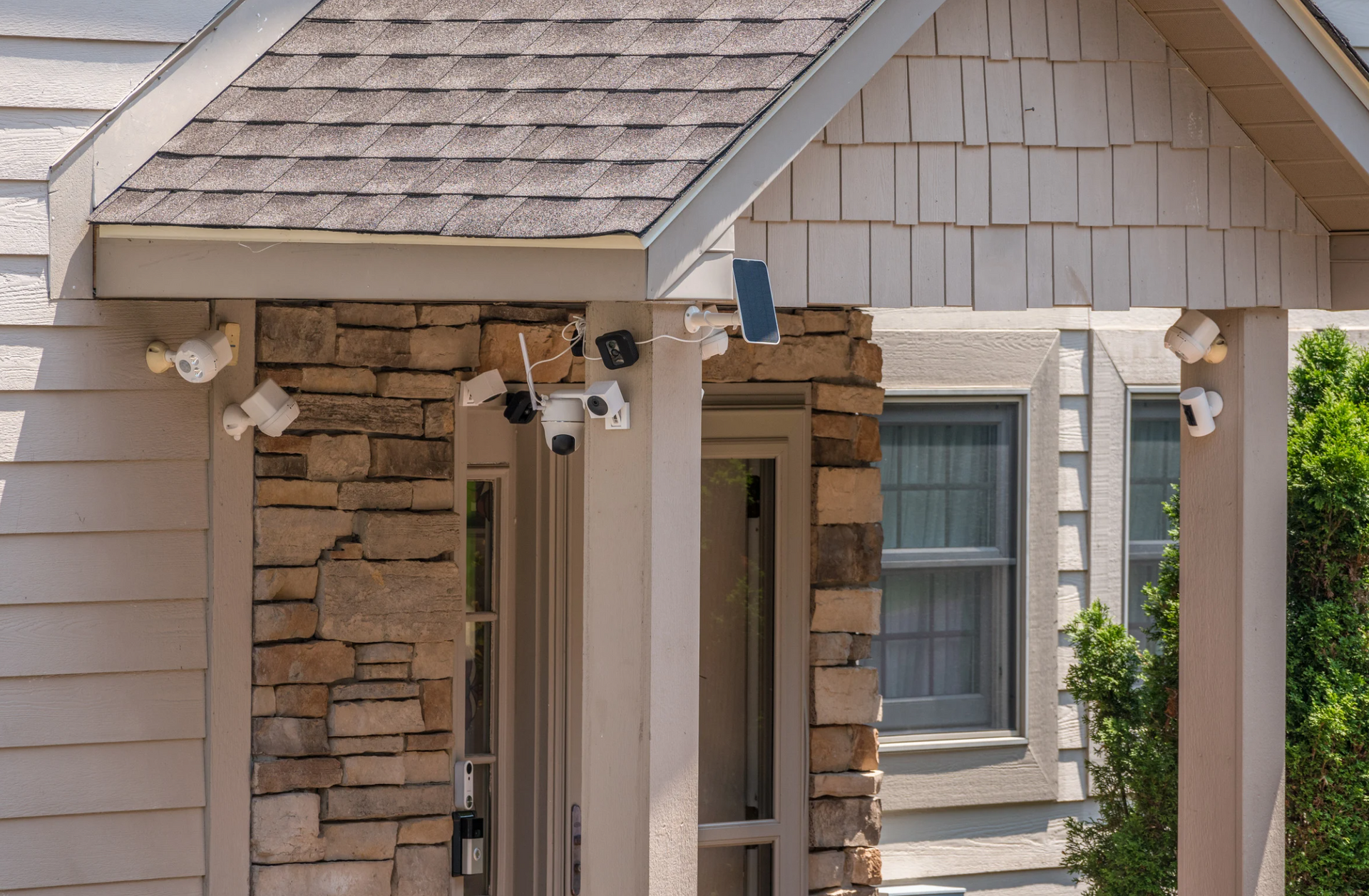 A house with a stone wall and a porch with security cameras on it.