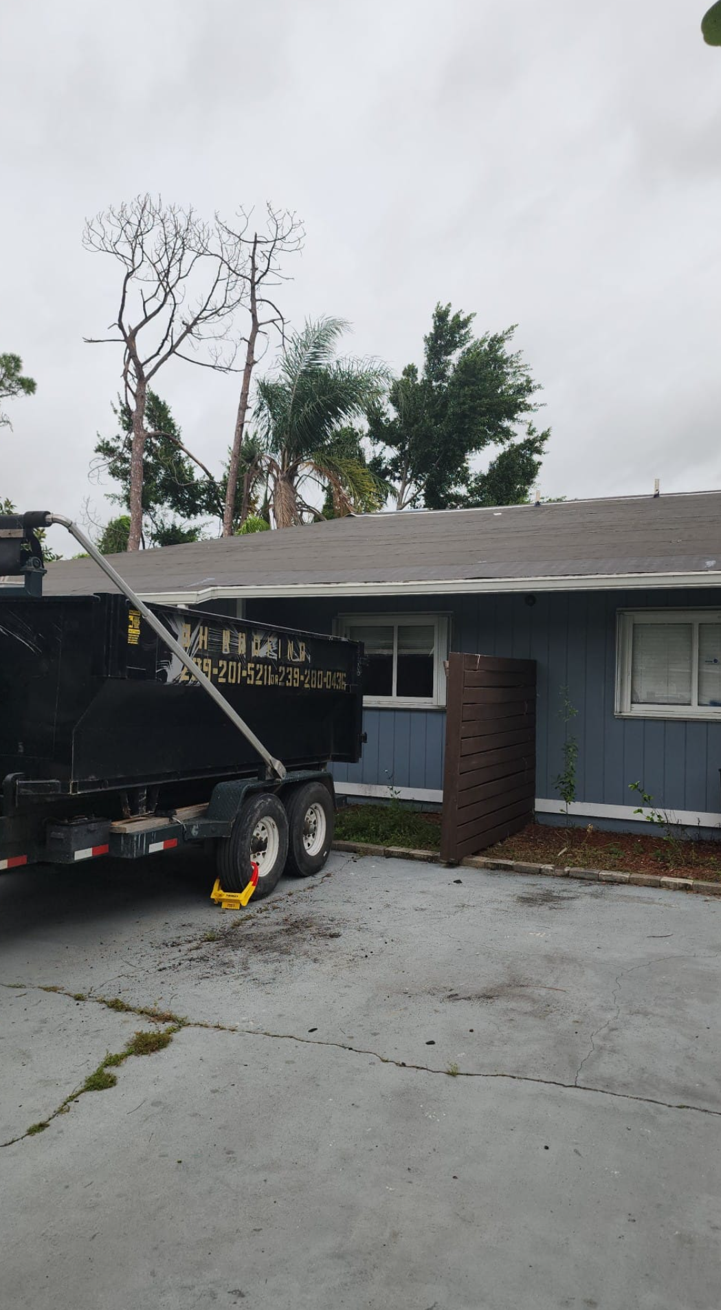 A dump truck is parked in front of a blue house.