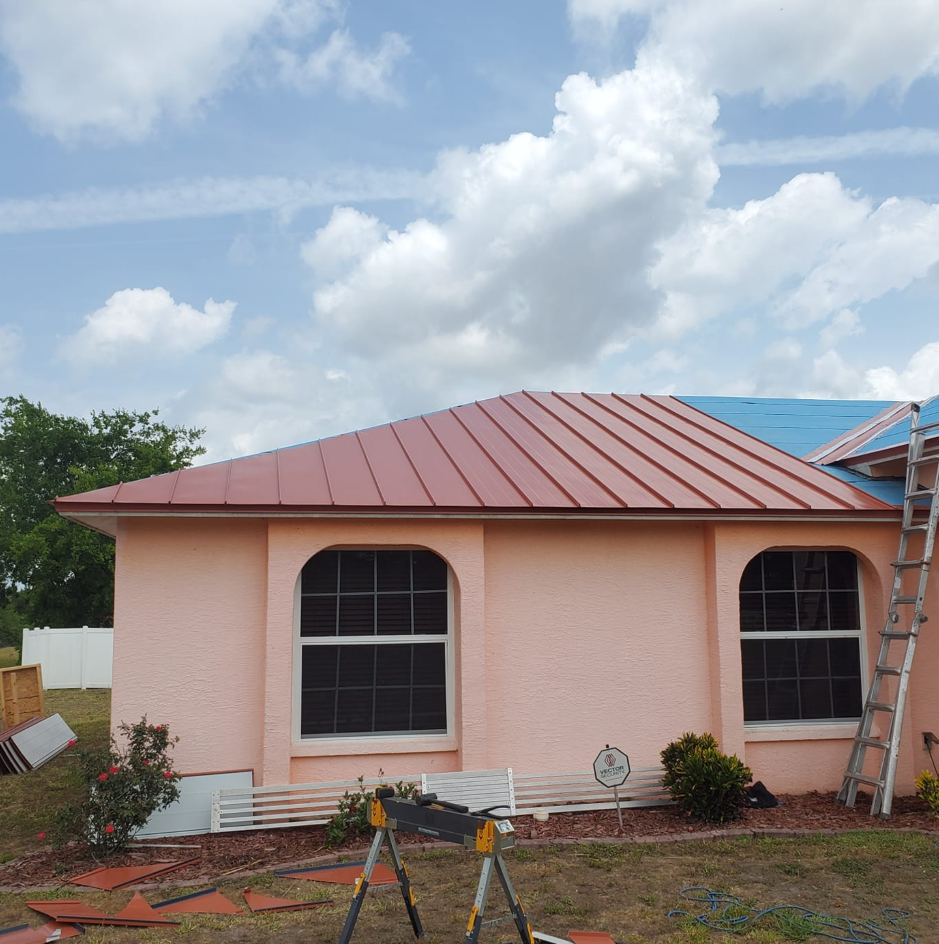 A pink house with a red roof is being painted