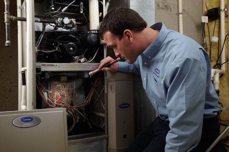 Furnace technician inspects a Carrier furnace.