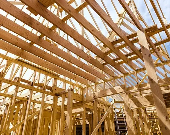 The inside of a wooden building under construction with a vaulted ceiling.