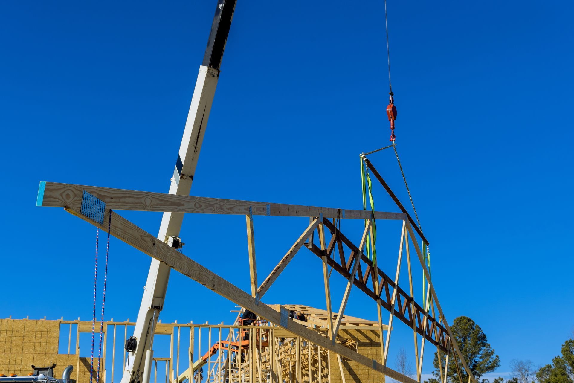 A crane is lifting a wooden structure on a construction site.
