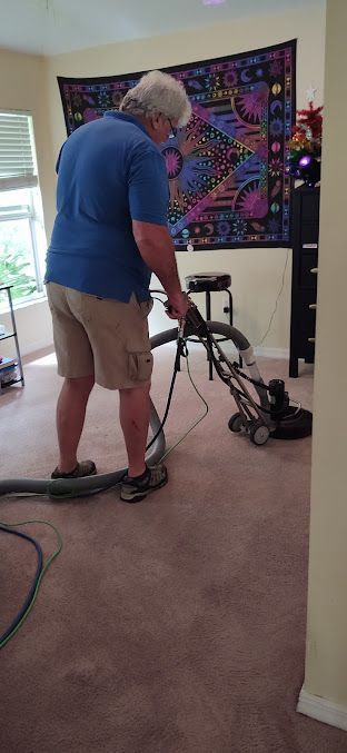 A man is using a vacuum cleaner to clean a carpet in a living room.