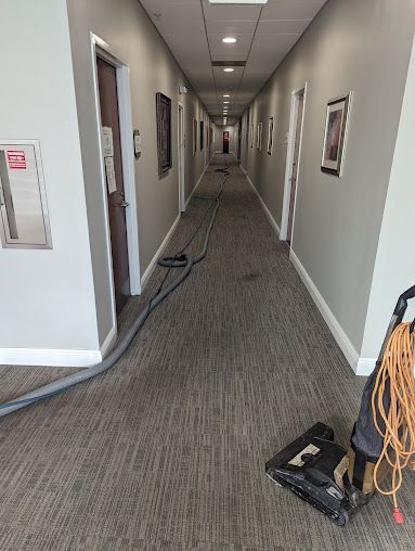 A vacuum cleaner is sitting in the middle of a long hallway.