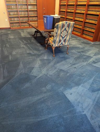 A chair is sitting in front of a table in a library