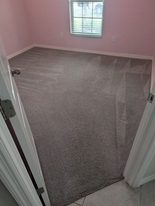 A bedroom with a carpeted floor and a window.