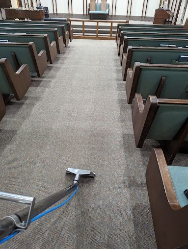 A vacuum cleaner is cleaning the carpet in a church.