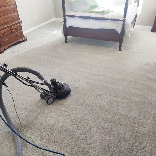 A vacuum cleaner is sitting on a carpet in a bedroom next to a bed.