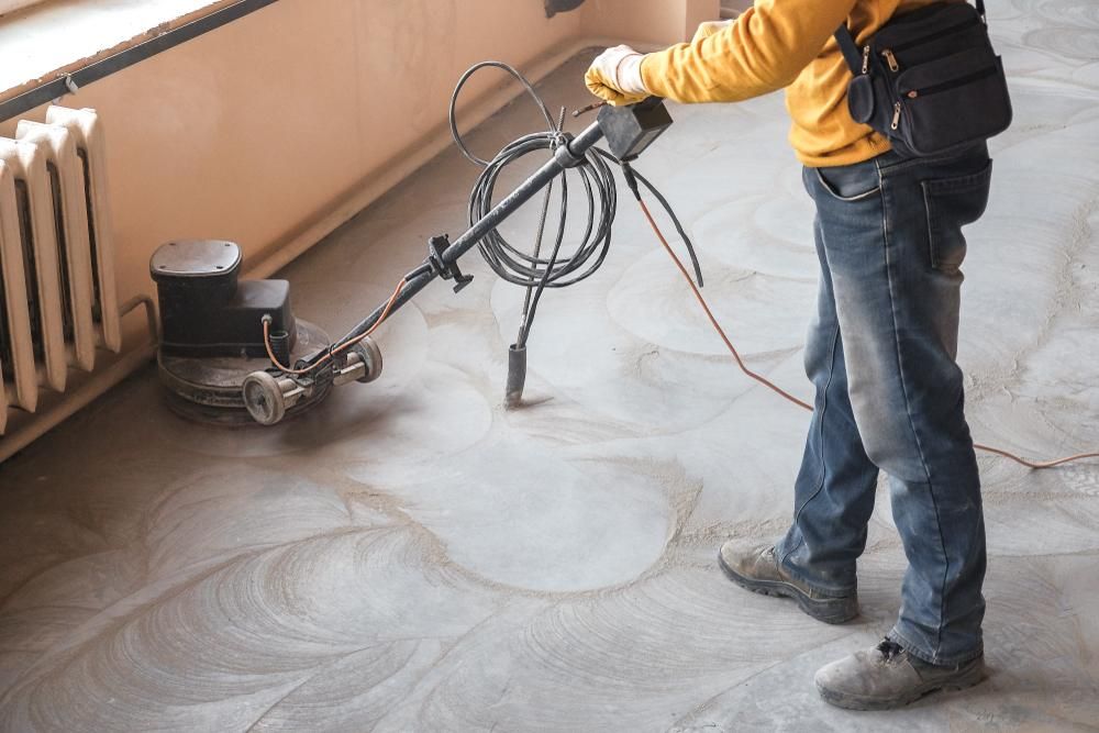 A Man Is Using a Machine to Polish a Concrete Floor — TNT Floor Removal & Demolition in Tewantin, QLD