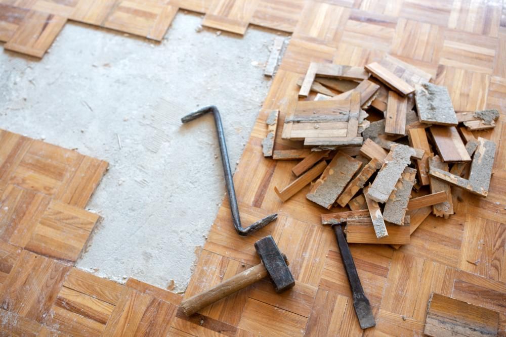 A Hammer and Chisel Are Laying on A Wooden Floor — TNT Floor Removal & Demolition in Tewantin, QLD