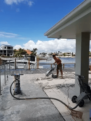 A Man Is Using a Machine to Remove Flooring of A Walkway — TNT Floor Removal & Demolition in Tewantin, QLD