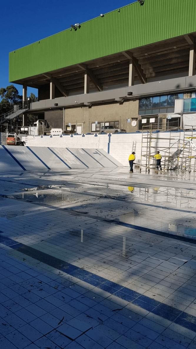 A Large Building with A Green Roof Is Being Built Next to A Swimming Pool — TNT Floor Removal & Demolition in Tewantin, QLD