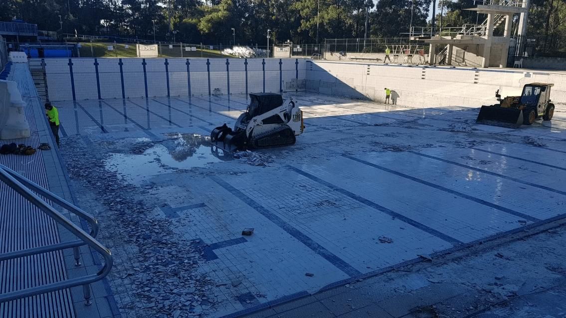 A Bulldozer Is Cleaning the Bottom of A Swimming Pool — TNT Floor Removal & Demolition in Tewantin, QLD