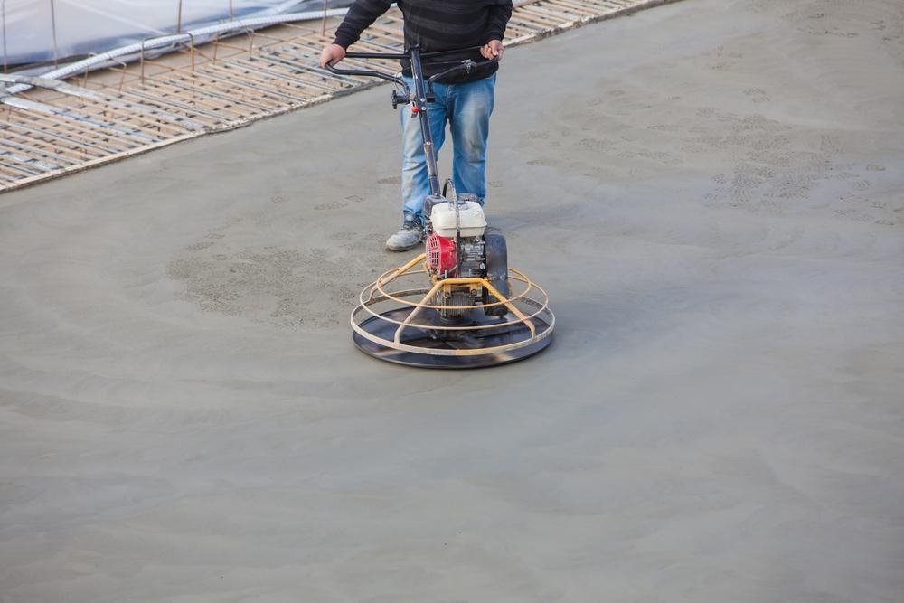 A Man Is Using a Machine to Finish Concrete on A Construction Site — TNT Floor Removal & Demolition in Tewantin, QLD