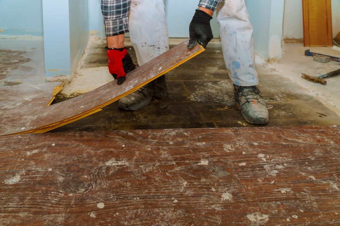 A Man Is Laying a Wooden Floor with A Trowel — TNT Floor Removal & Demolition in Tewantin, QLD