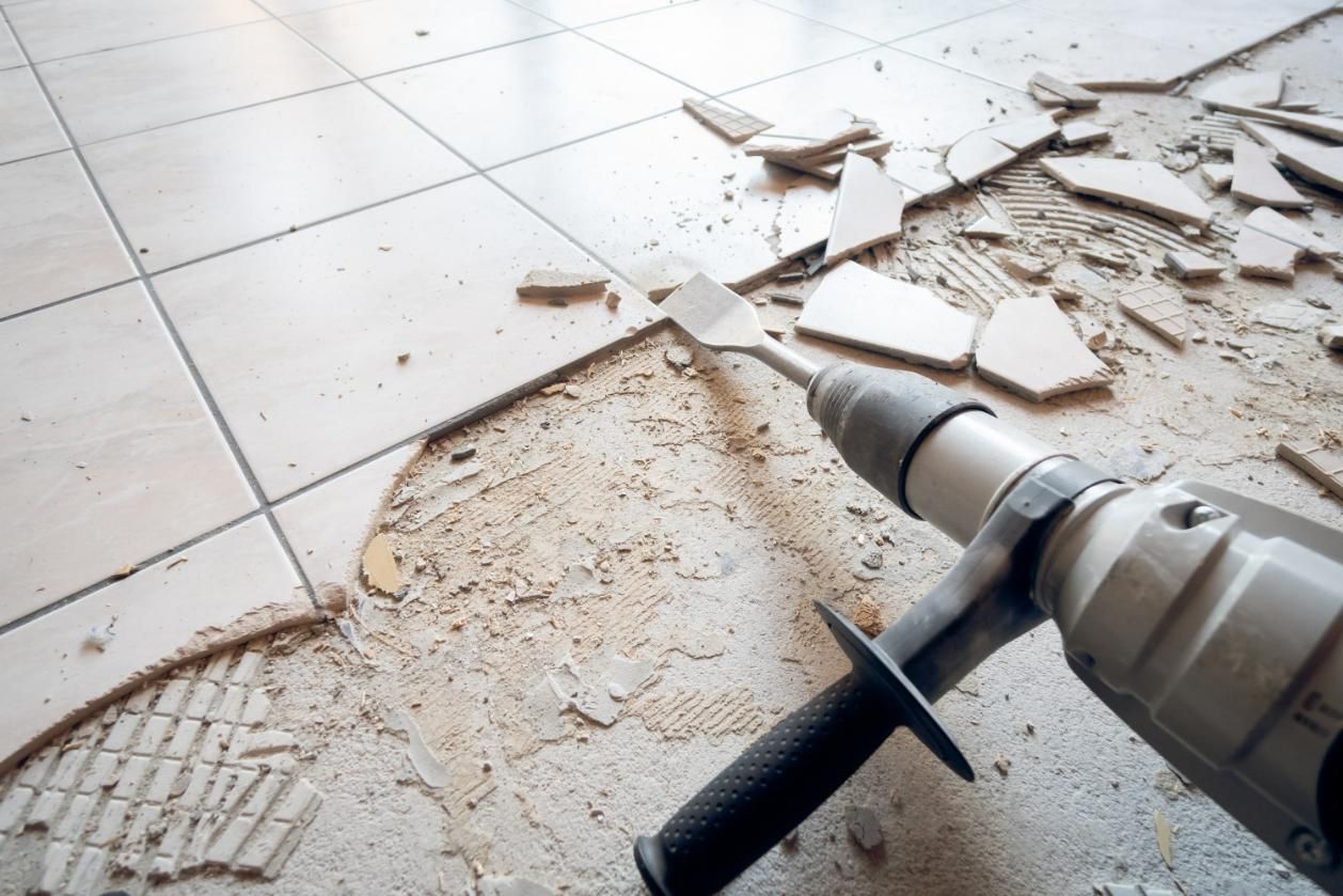 A Drill Is Being Used to Remove Tiles from The Floor — TNT Floor Removal & Demolition in Tewantin, QLD