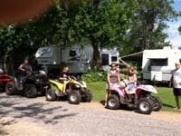 A group of people are riding atvs in a parking lot.