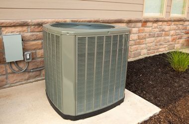 Outdoor HVAC unit beside a brick house wall and window on a concrete pad