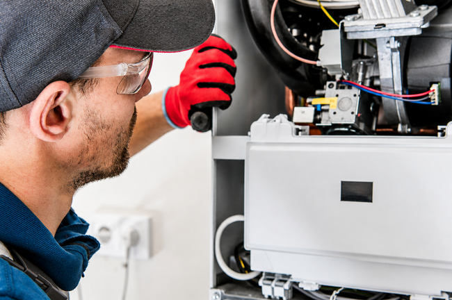 Technician inspecting an open furnace with wires and components exposed