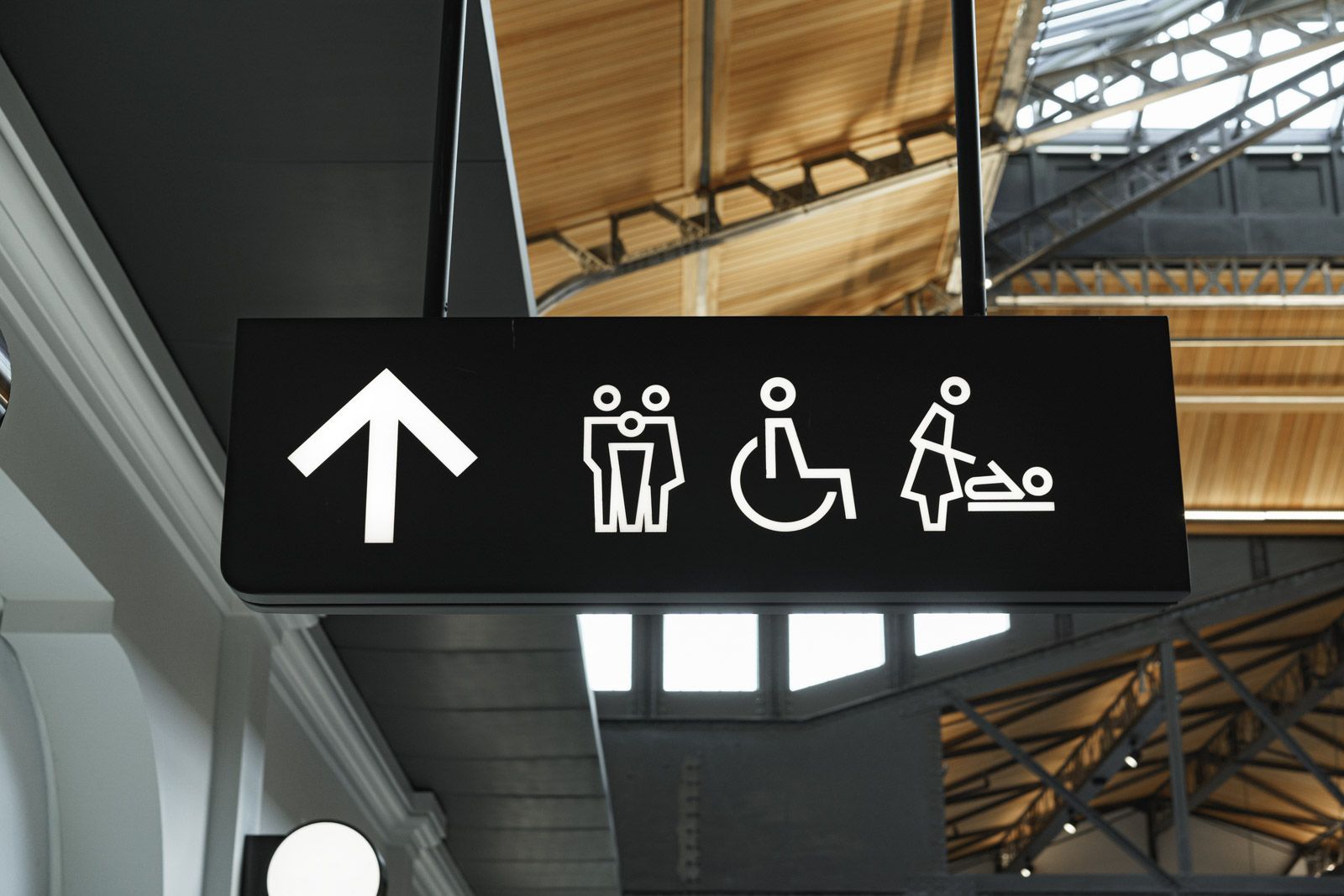 Von der Decke hängt ein schwarzes Schild mit einem nach oben zeigenden Pfeil.