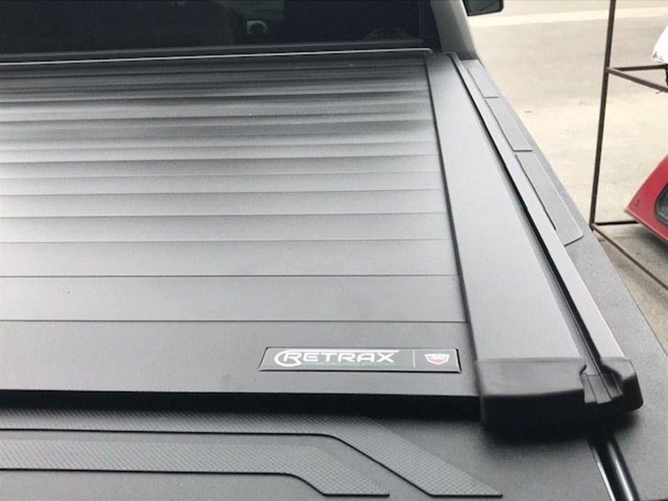 A black Retrax retractable tonneau cover installed on the bed of a pickup truck.