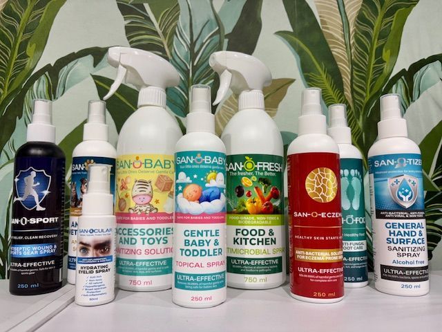 Various San-o-baby cleaning products in bottles, with spray nozzles, against a leafy backdrop.