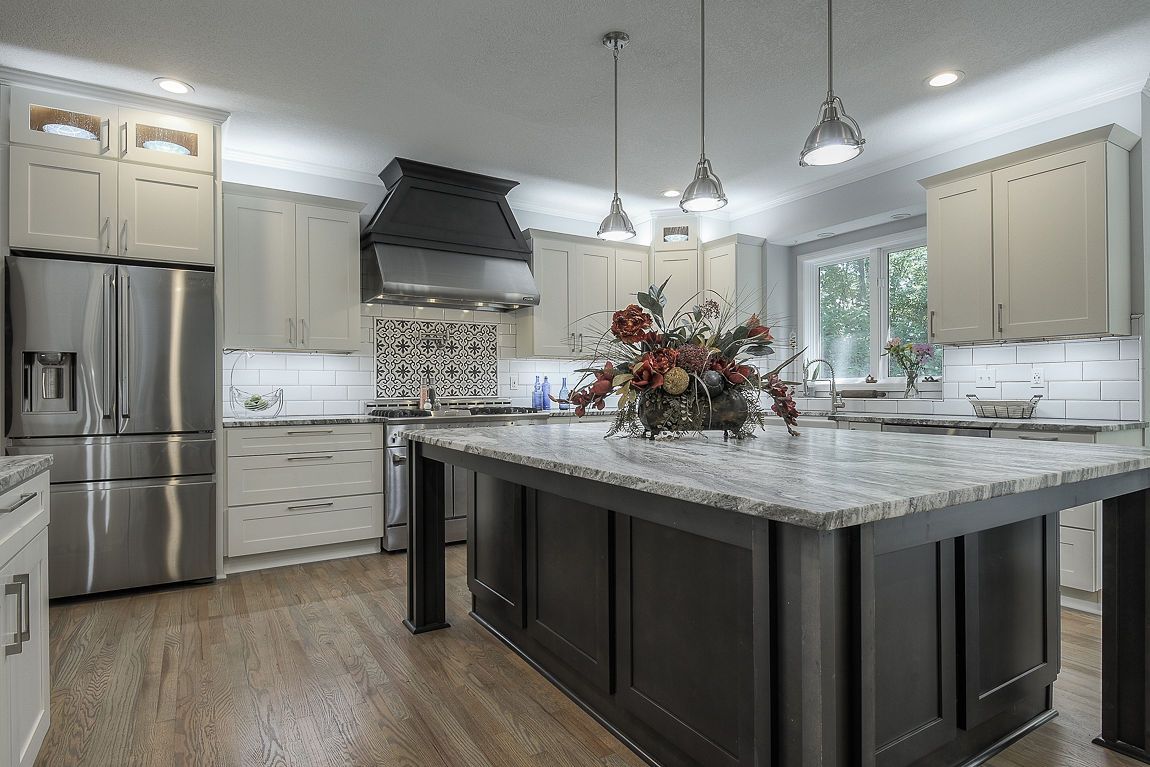 A kitchen with white cabinets , stainless steel appliances , a sink , and a large island.